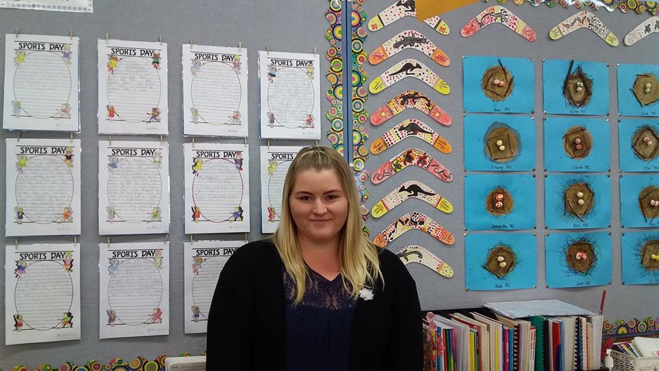 Female LSO standing in front of art samples made by students during her placement.