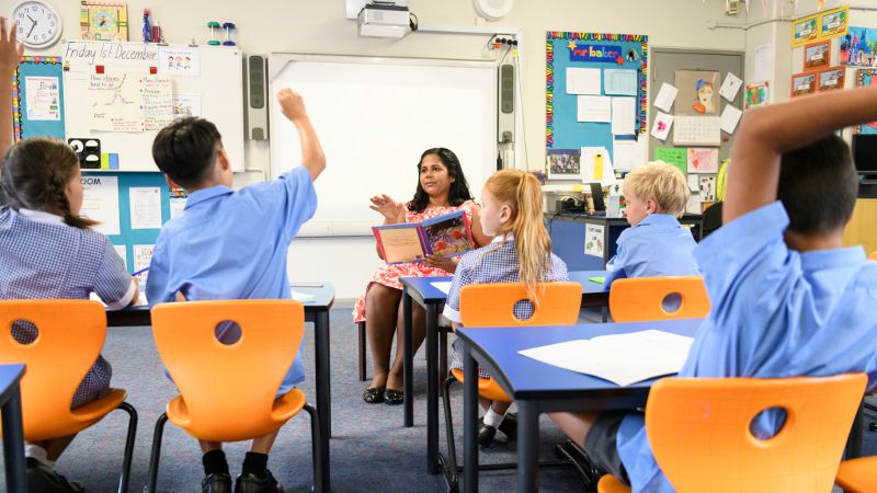 Teacher assistant reading and discussing a book with students.