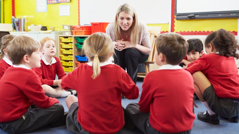 Teacher aide surrounded by a group of students.