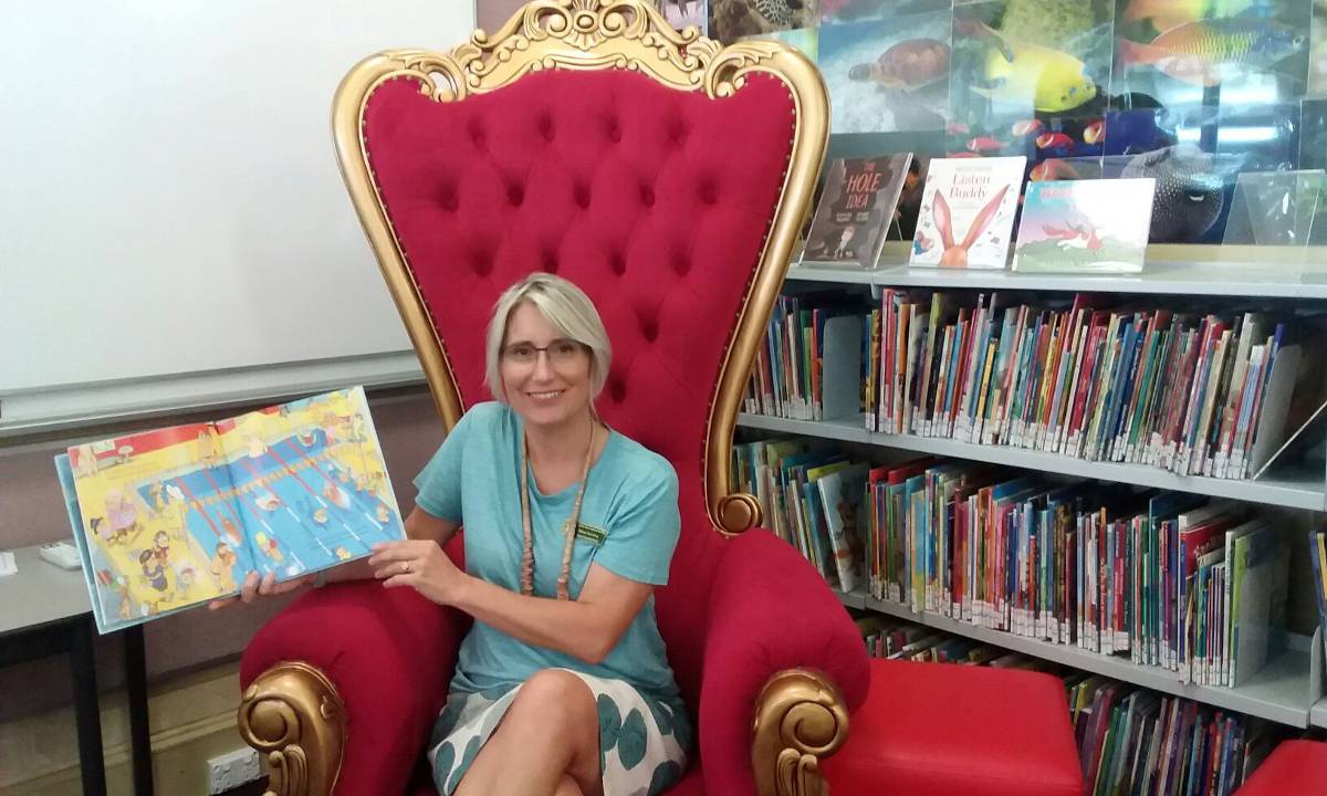 A teacher assistant sitting in the reading corner of a classroom..