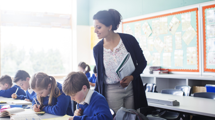 Education assistant supervising students in an australian classroom.