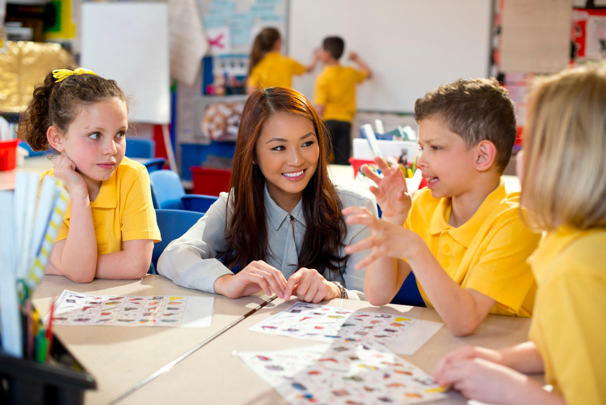 teacher aide helping several children in a school