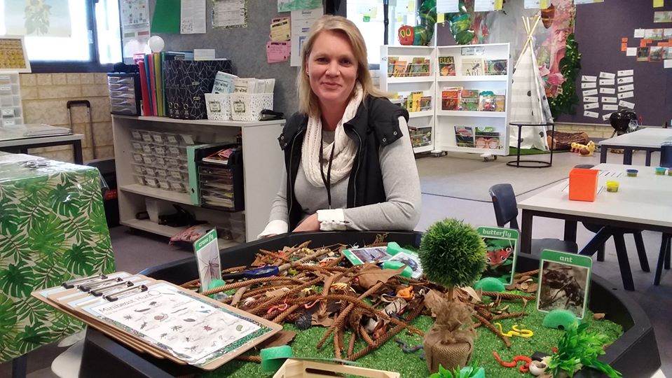 teacher aide at desk in front of resources for teaching kids about animals and plants.