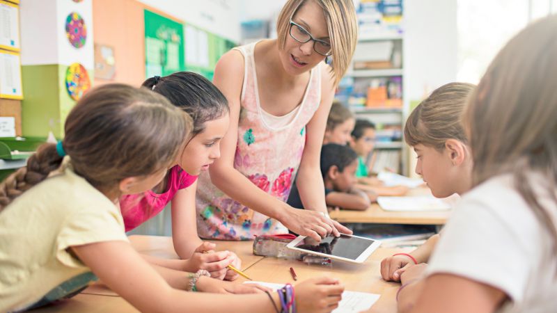 Teacher aide working with students in a classroom setting.