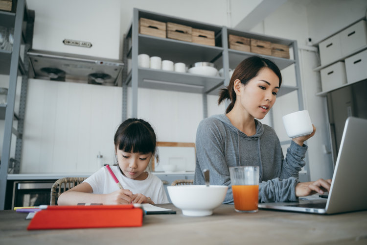 Mother studying on a laptop while supervising young child.